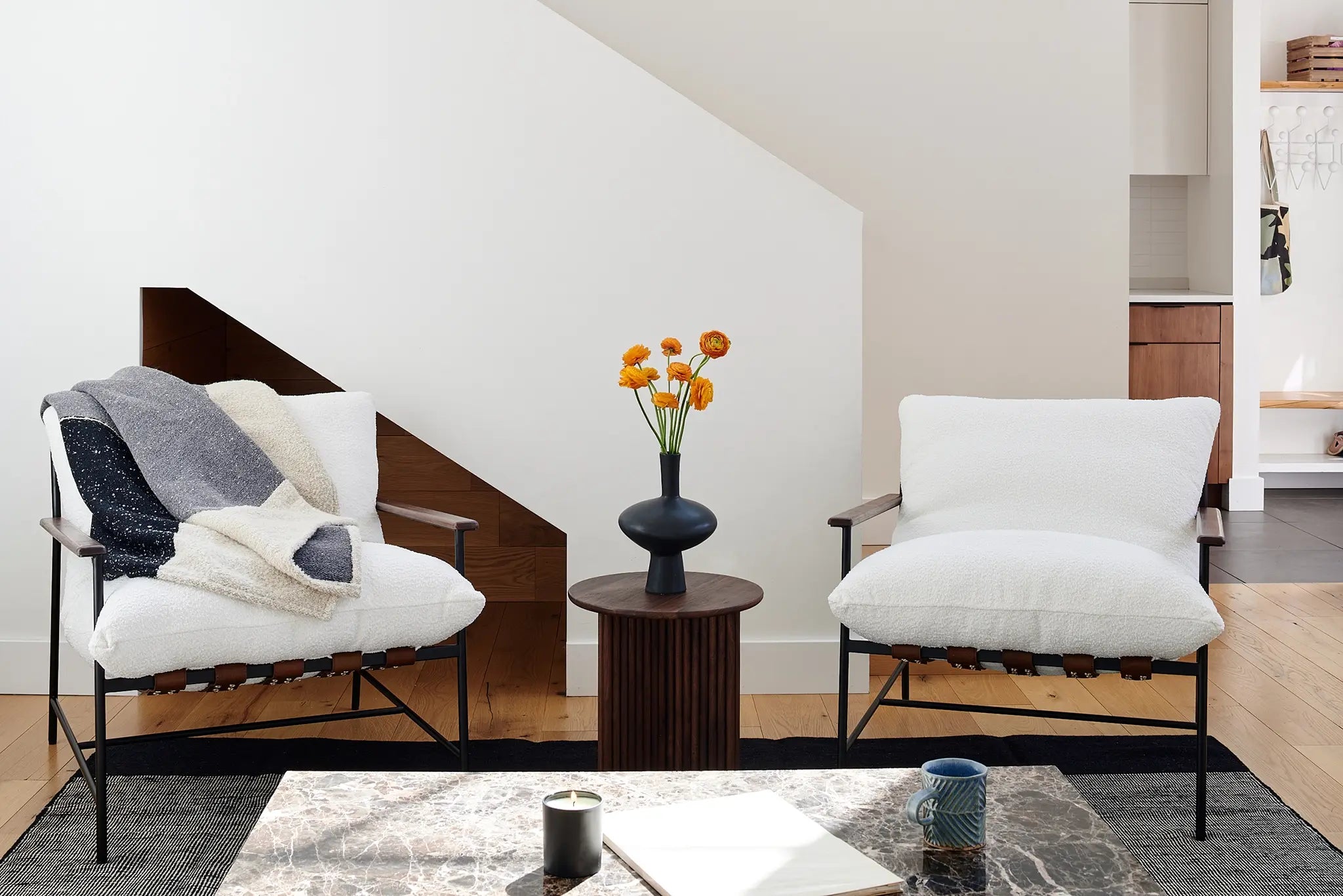 A cozy living room featuring two elegant chairs and a vibrant vase filled with fresh flowers.